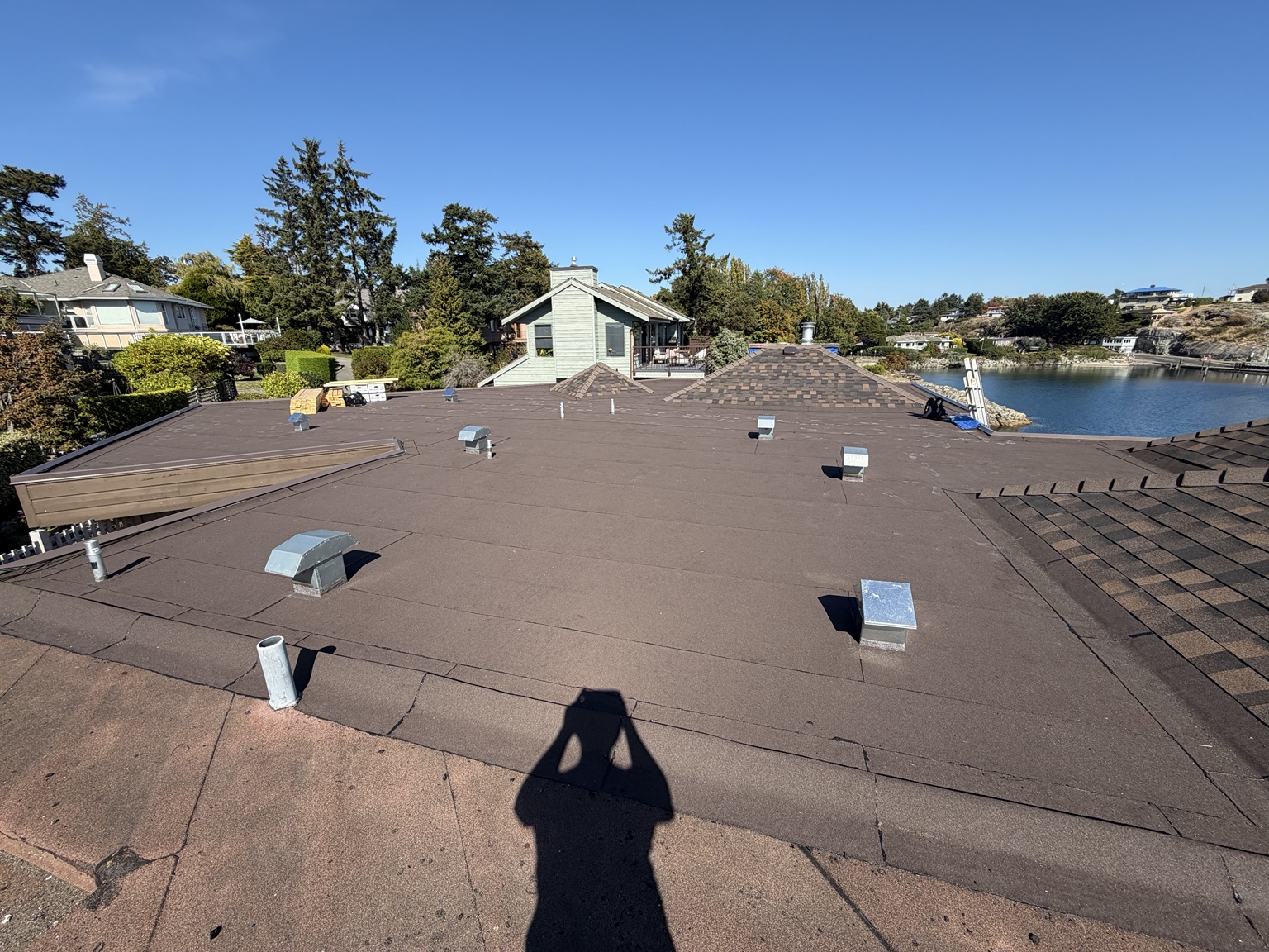 Flat roof with membrane surface, metal vents and asphalt-shingle roof sections
