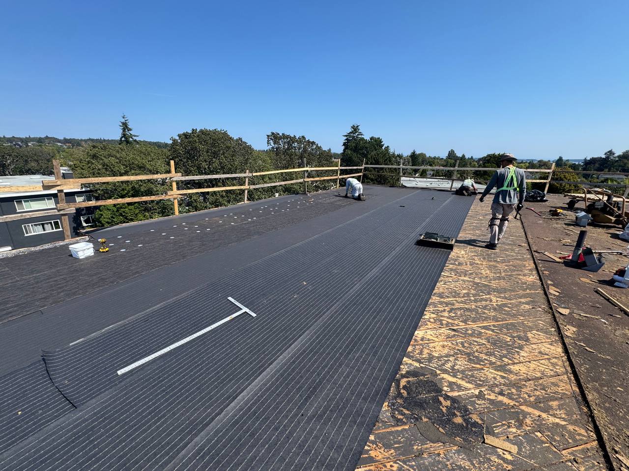 Crew rolling out new membrane over a prepared roof deck