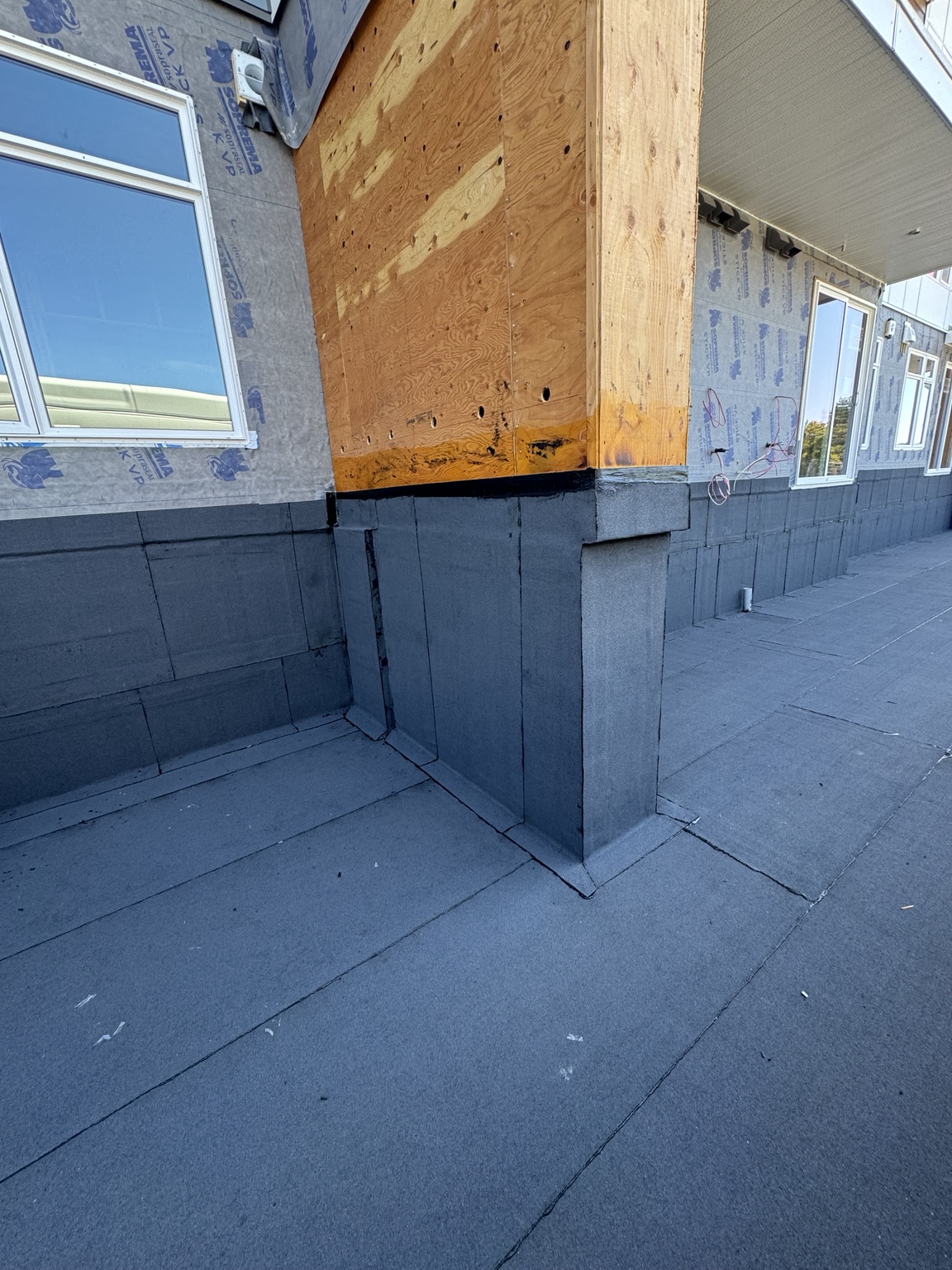 Membrane-clad column and wall base details along a building perimeter under construction