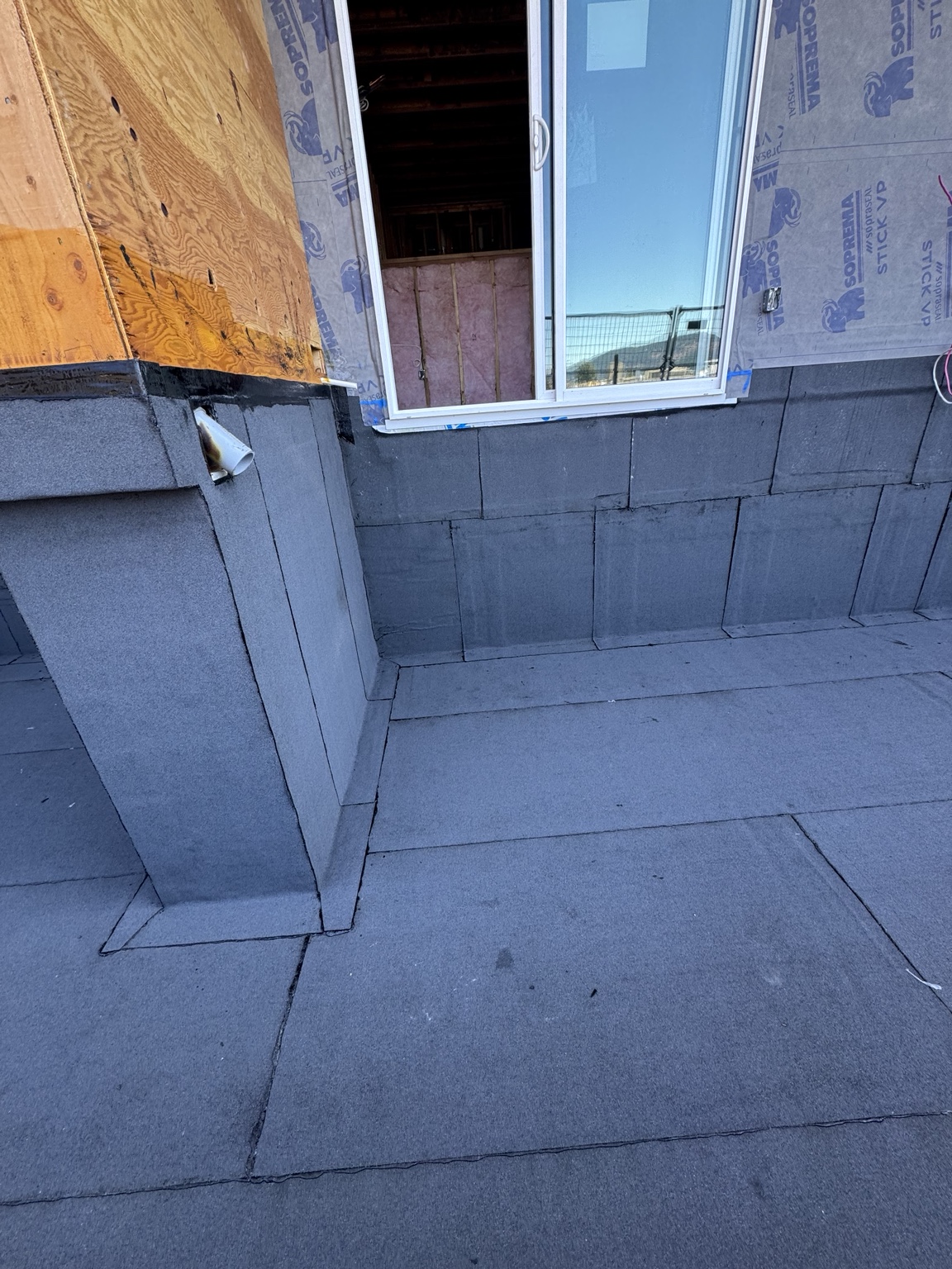 Membrane upstands and transitions at a wall corner beside a sliding door opening